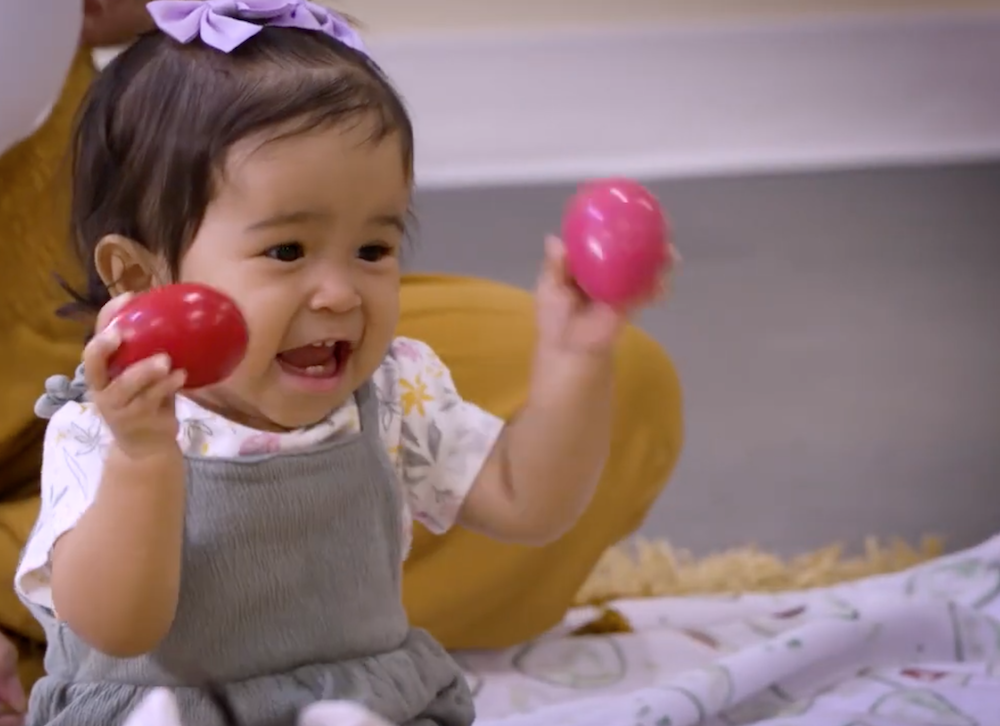 An 18-month-old girl shakes egg shakers during a Kindermusik Top Program class.